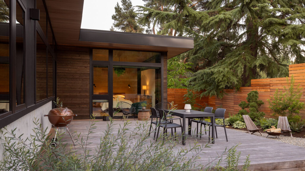 Outdoor patio of Cedar Cove project with a wood and glass building, landscaping, and patio.